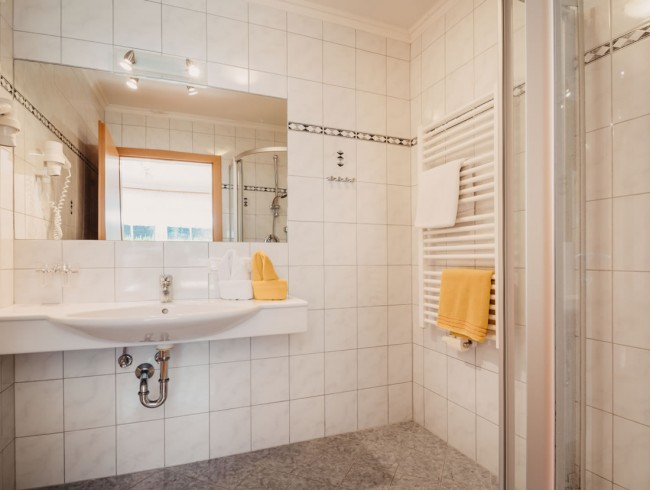 Badezimmer mit Dusche, Waschbecken und Handtuchwärmer